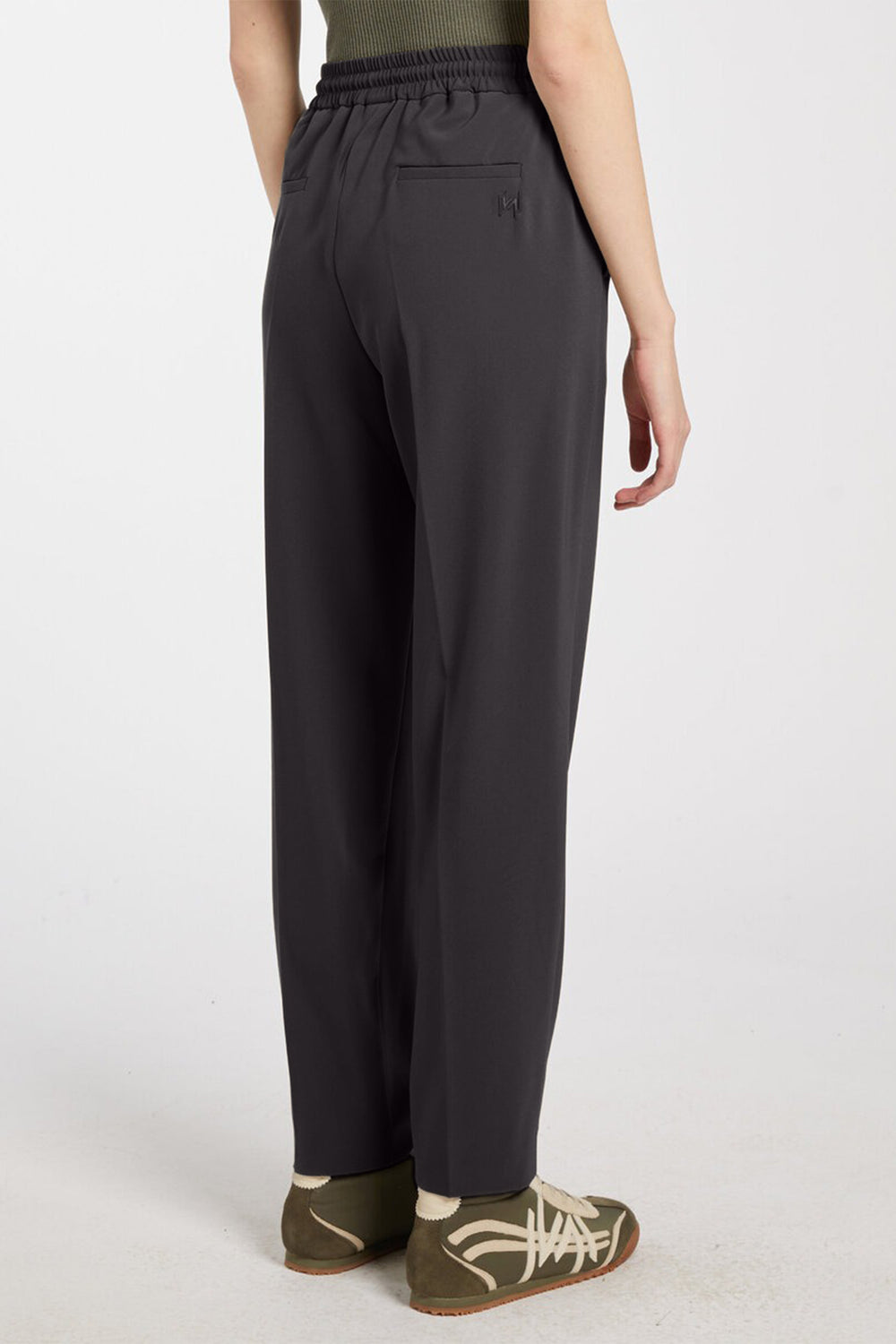 Dark gray pants worn by a person on a white background