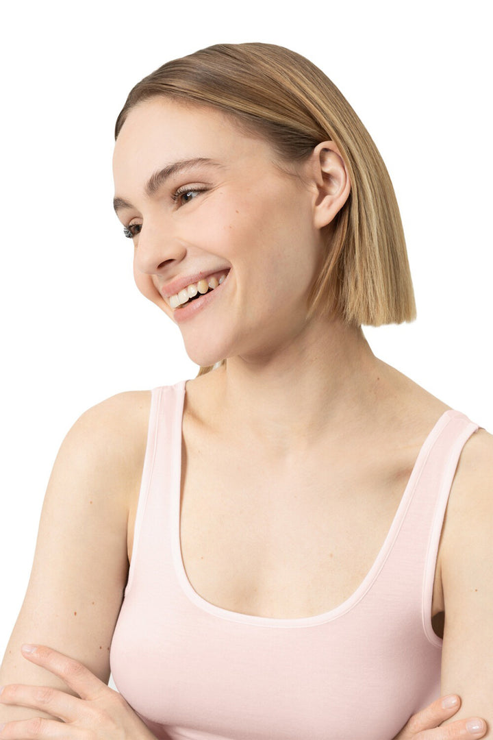 Woman wearing a light pink tank top against a white background