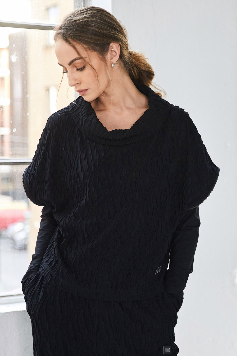 Woman wearing a black textured sweater in an indoor setting