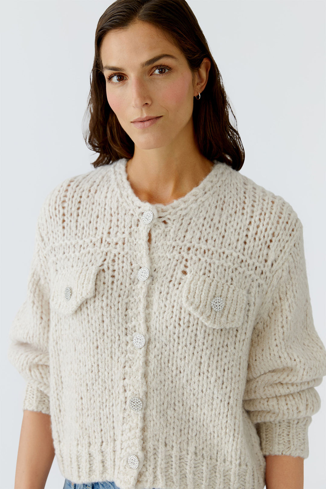Woman wearing a beige knitted cardigan against a white background