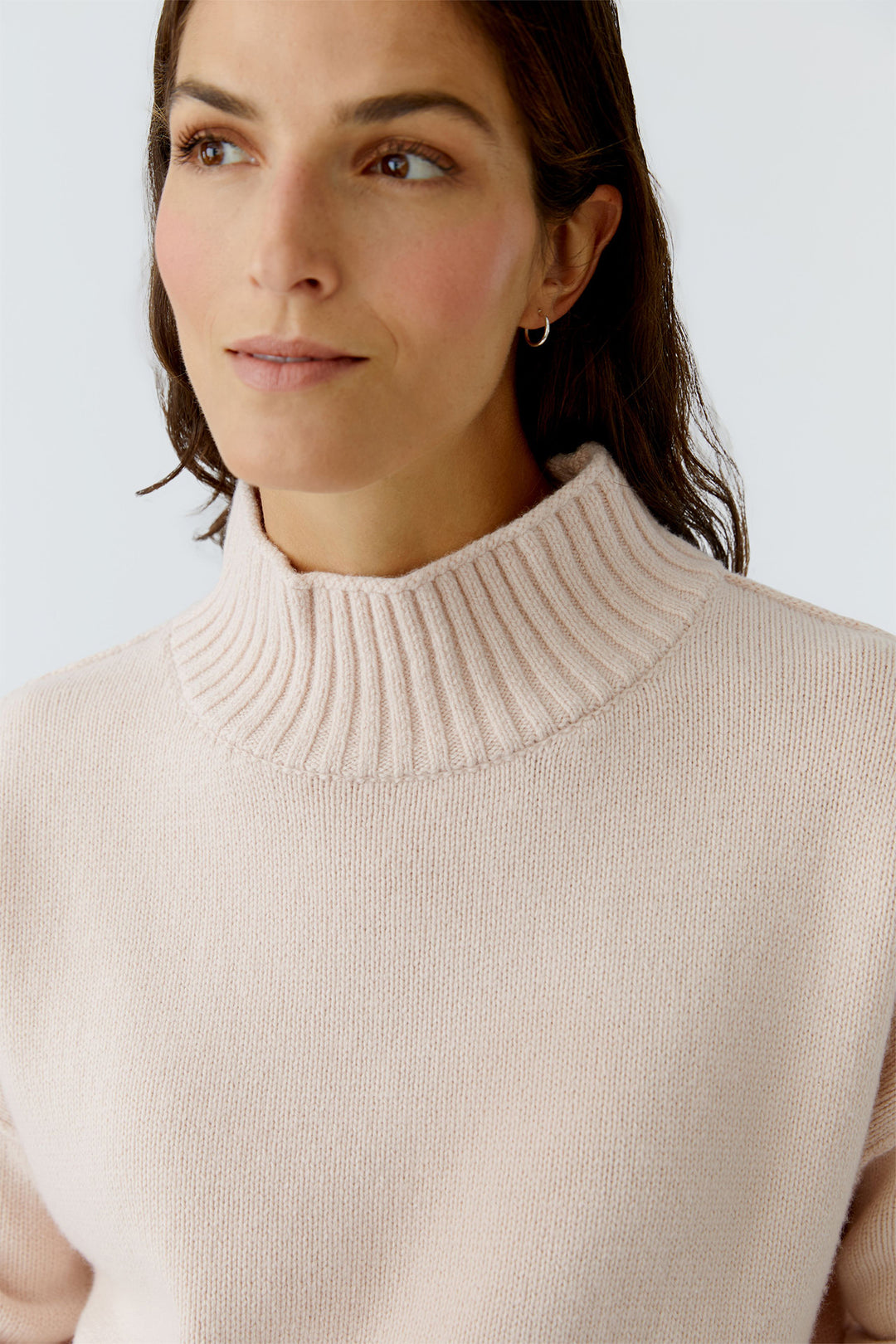 Woman wearing a beige sweater against a light background