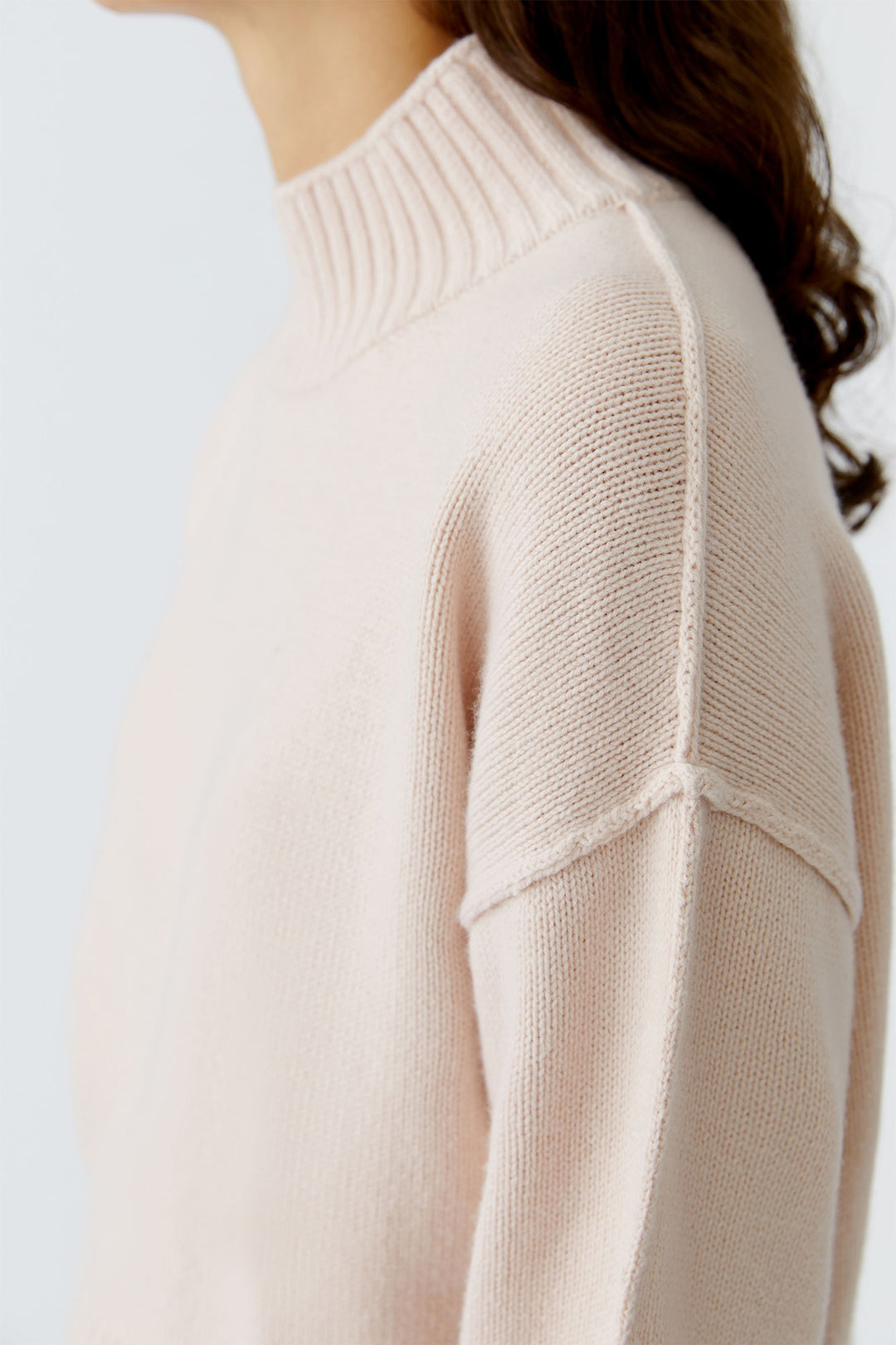 Close-up of a person wearing a light pink sweater on a white background