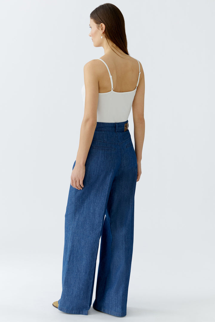 Woman wearing a white top and blue wide-leg pants on a white background