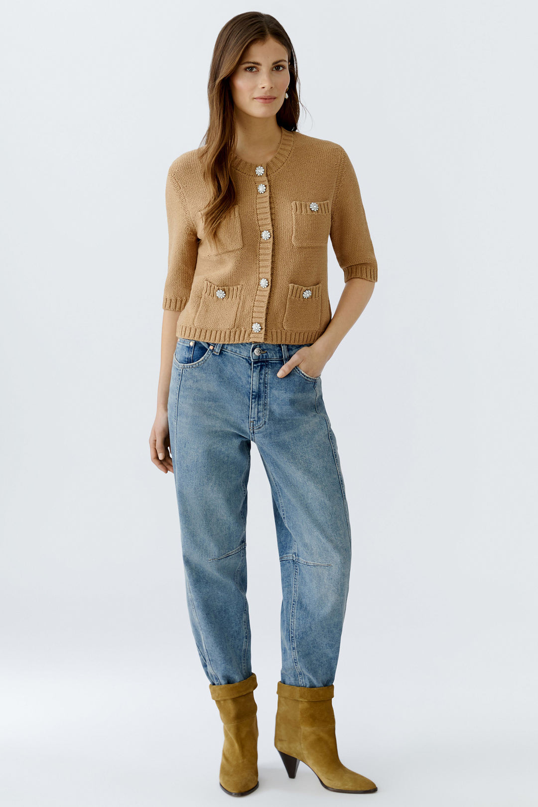 Woman wearing a brown cardigan, blue jeans, and yellow boots on a white background