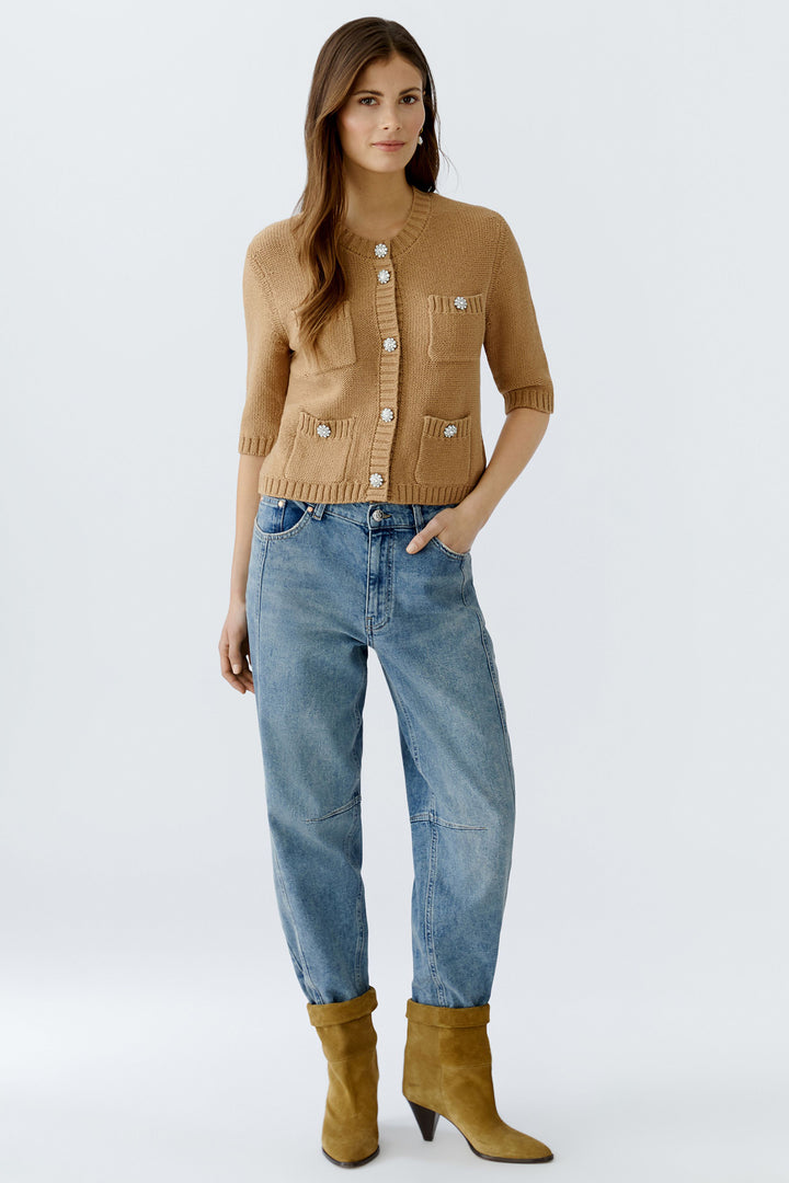 Woman wearing a brown cardigan, blue jeans, and yellow boots on a white background