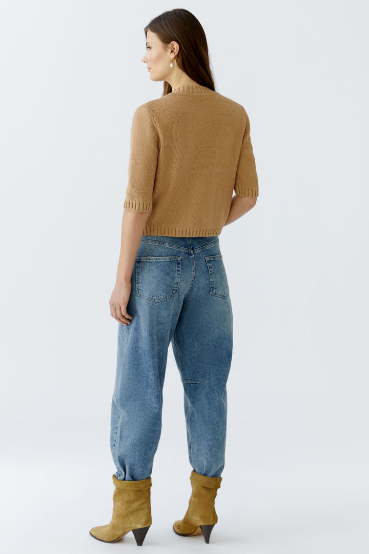 Woman wearing a brown sweater and blue jeans with yellow boots on a white background