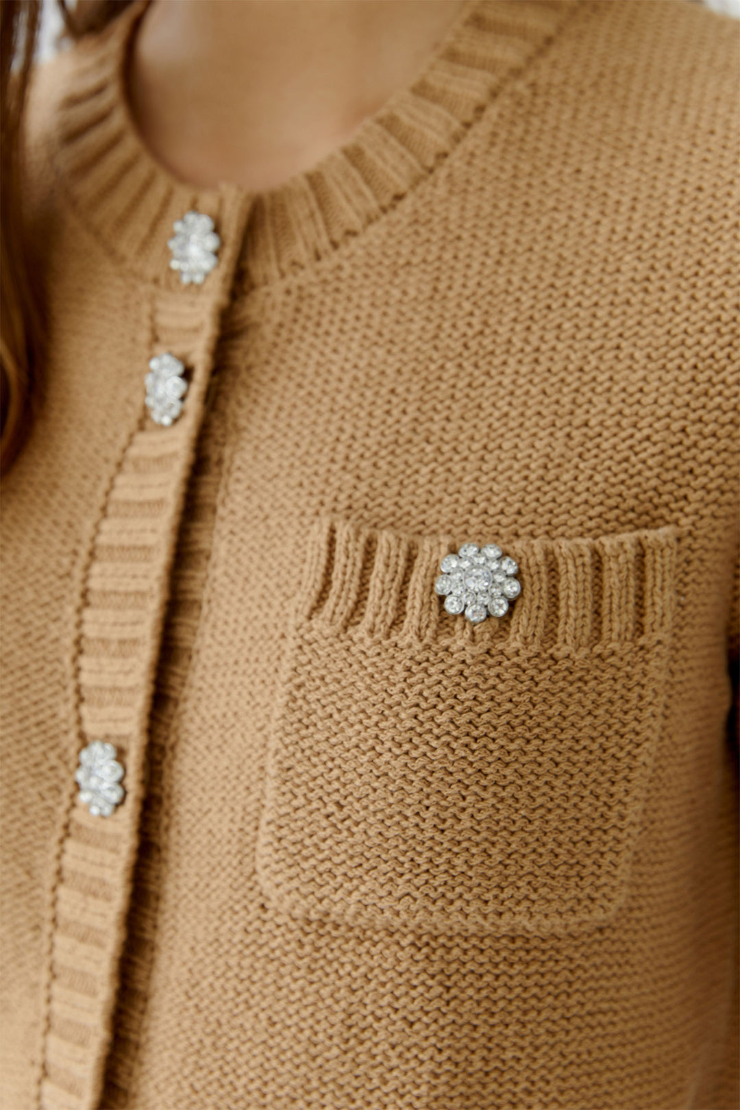 Close-up of a brown knitted cardigan with decorative buttons.