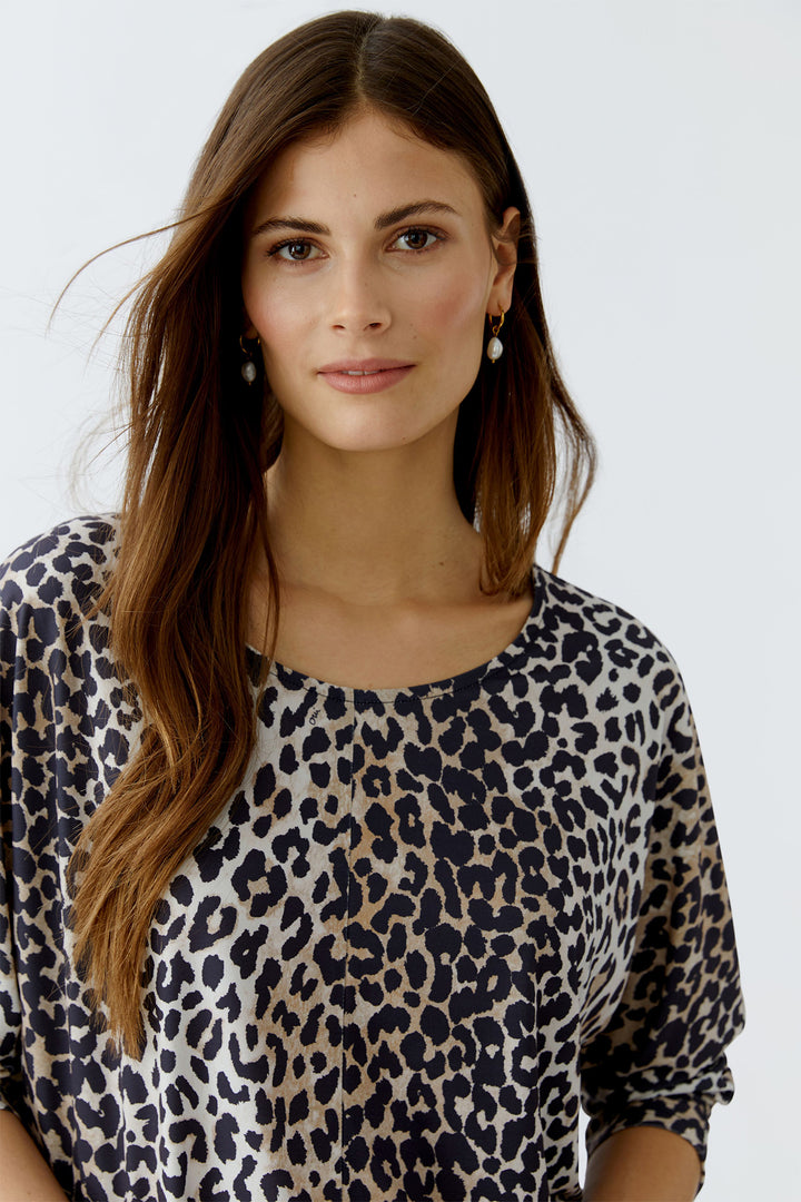 Woman wearing a leopard print top against a white background