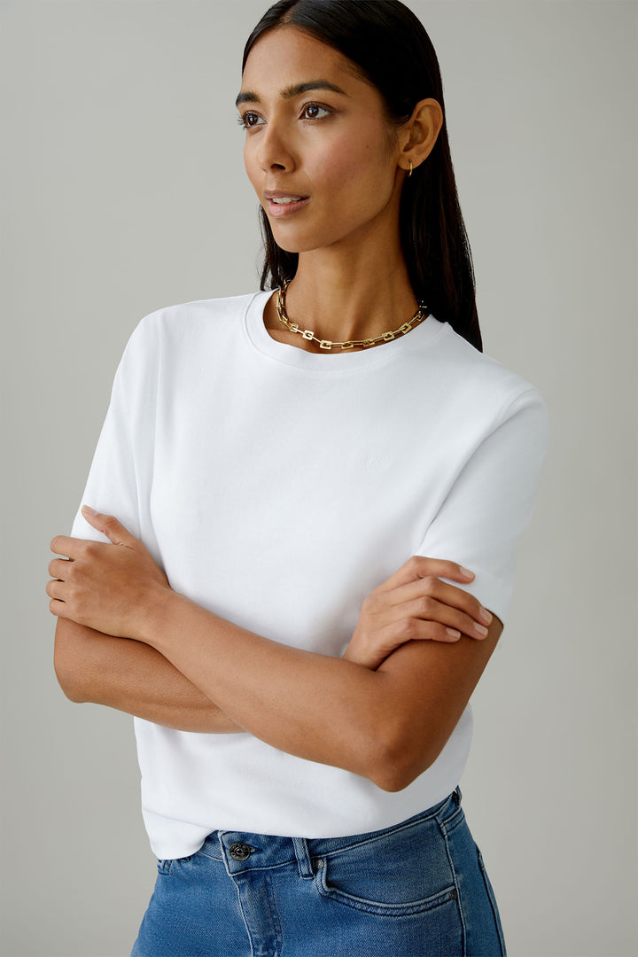 Woman wearing a white t-shirt and blue jeans with a neutral background