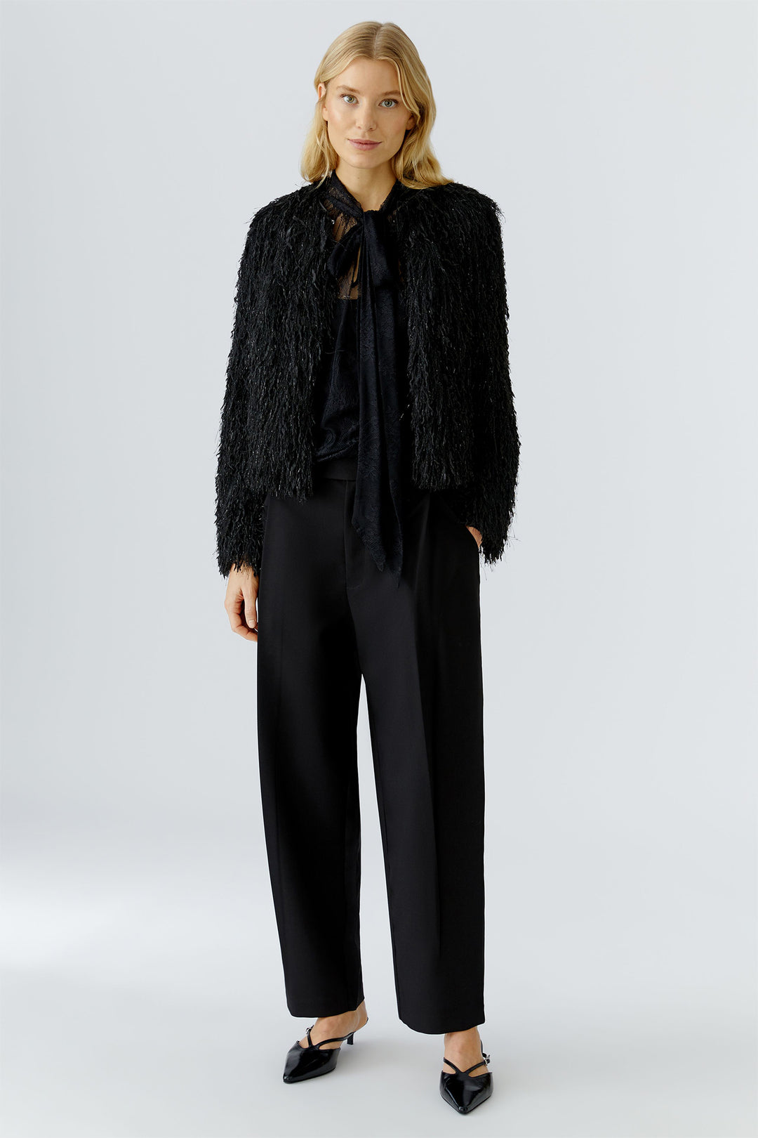 Woman wearing a black textured jacket and pants on a white background