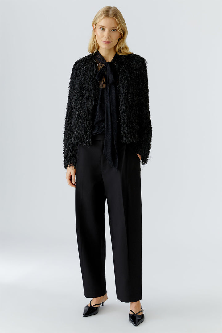 Woman wearing a black textured jacket and pants on a white background