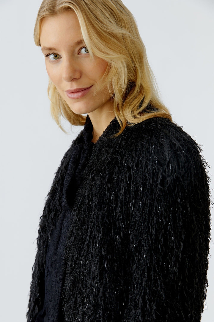 Woman wearing a black textured coat against a plain background