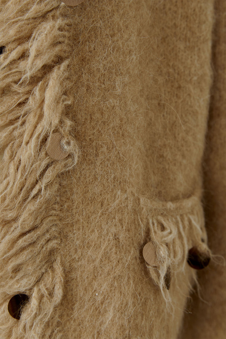 Close-up of a textured beige fabric with fringes and buttons.