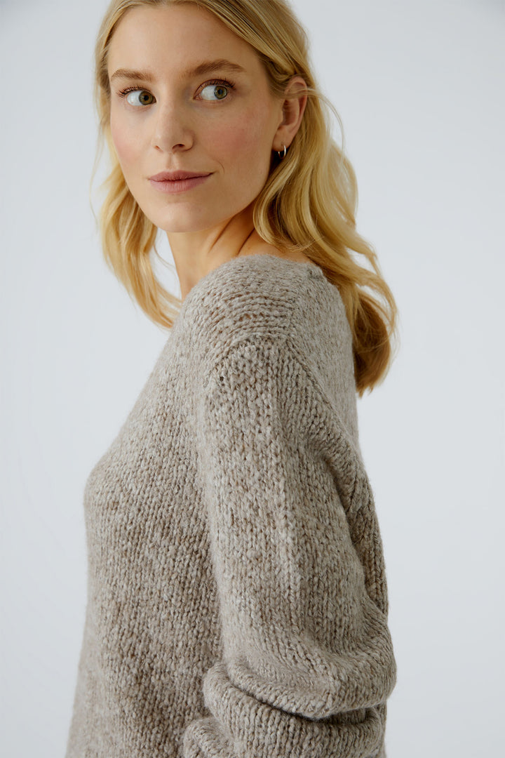 Woman wearing a beige knitted sweater against a white background