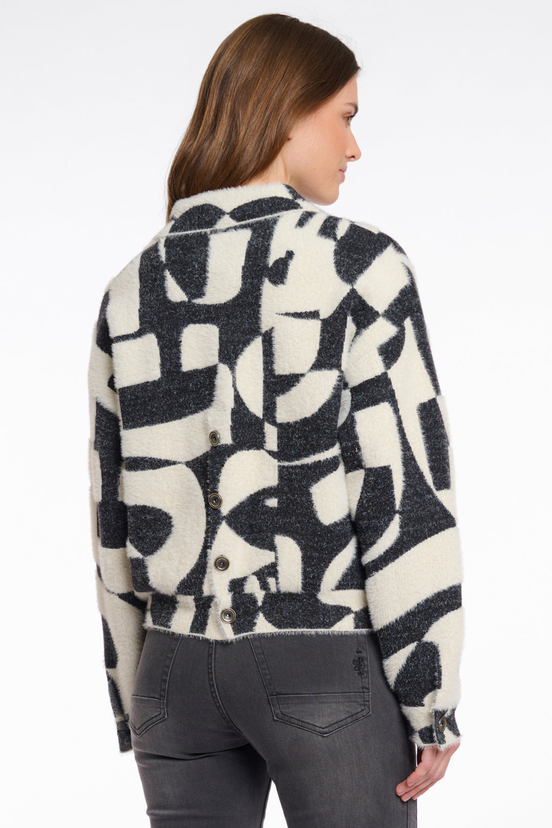 Woman wearing a patterned jacket with abstract design on a white background