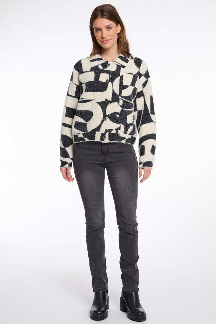 Woman wearing a patterned jacket and black jeans on a white background