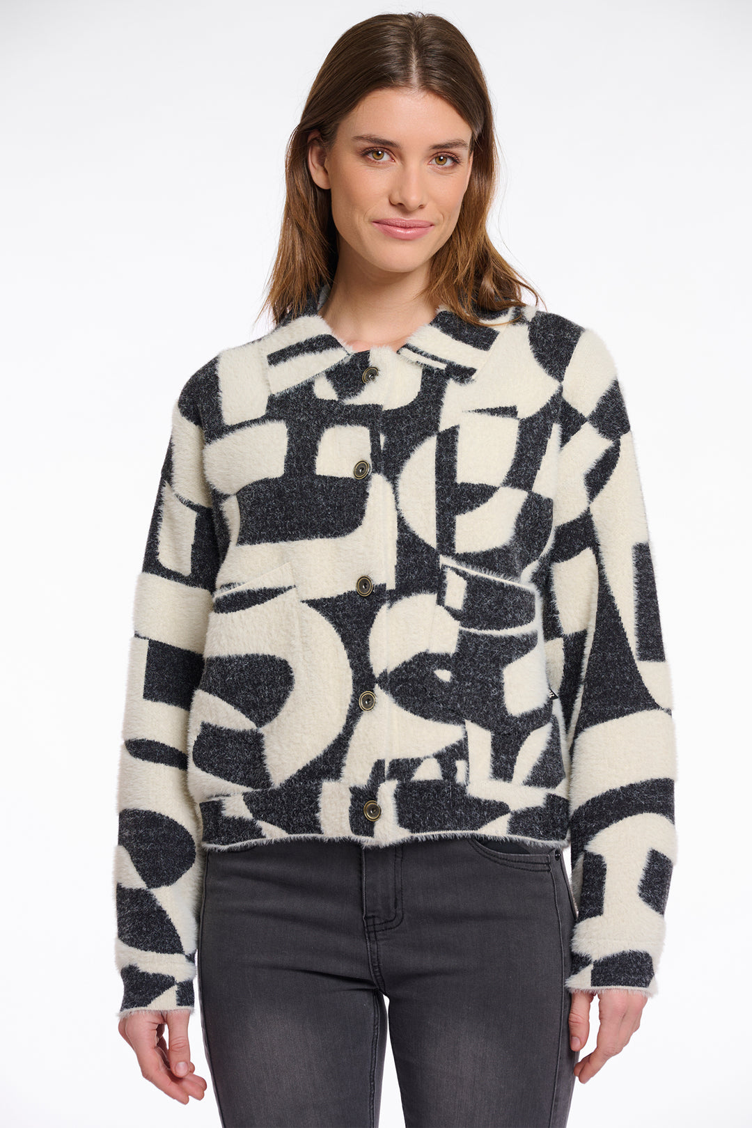 Woman wearing a black and white patterned jacket against a white background