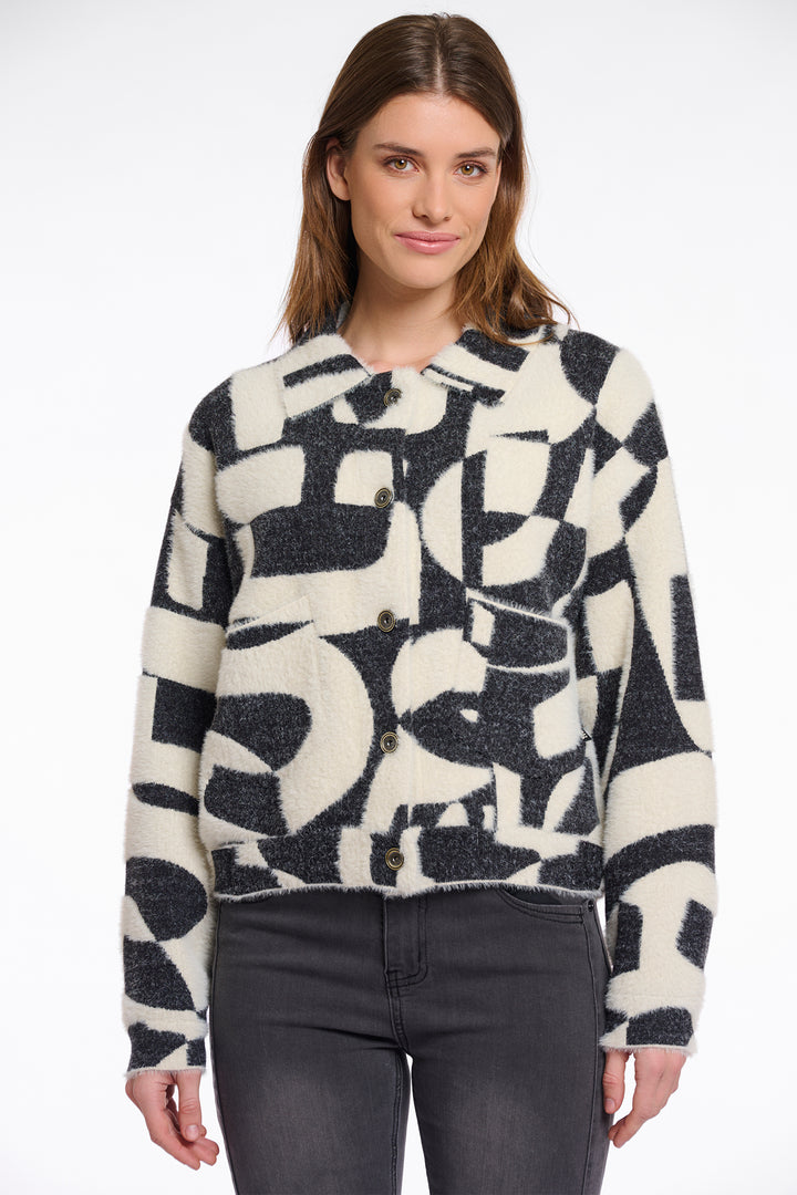 Woman wearing a black and white patterned jacket against a white background