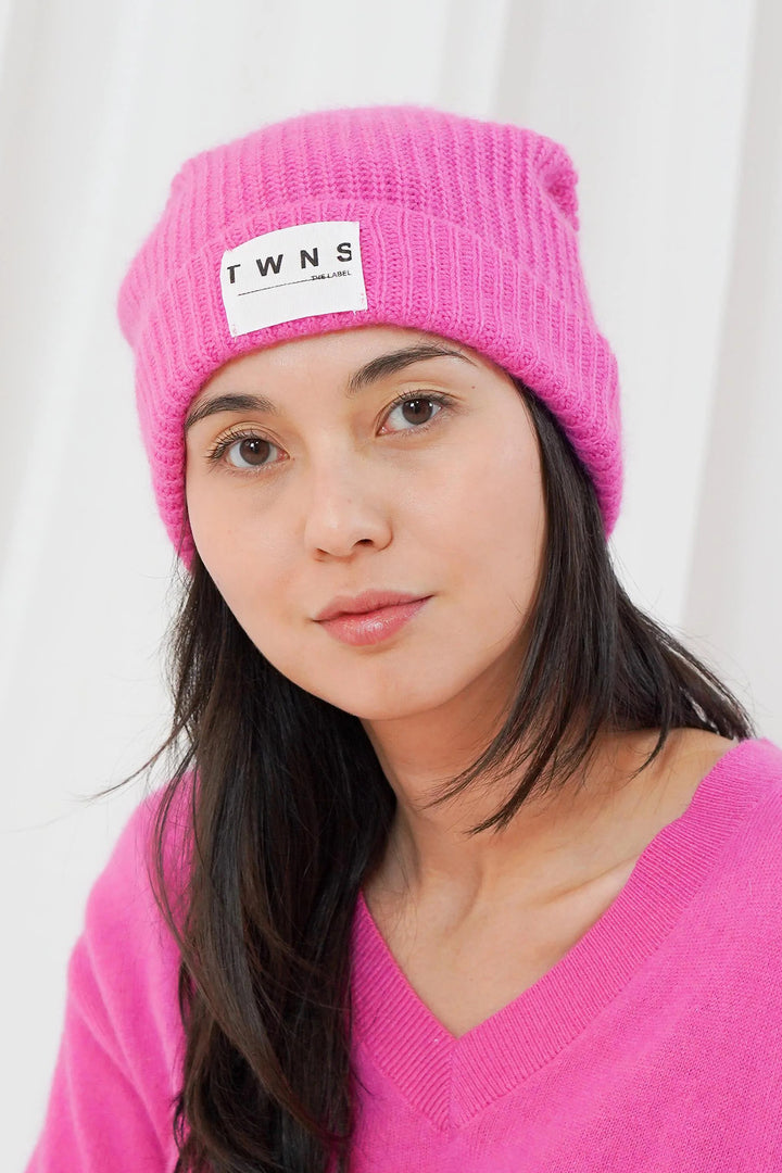 Twns The Label Littleton bubblegum pink ribbed beanie hat worn with a pink V-neck jumper at Olivia Grace Fashion