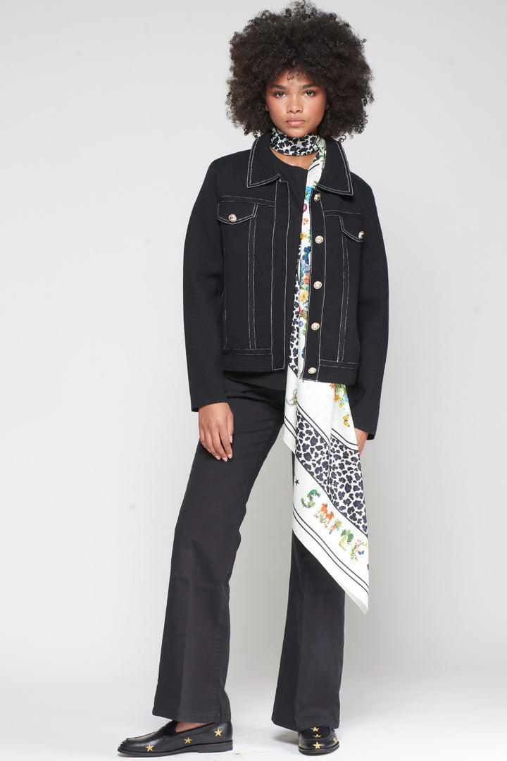 Person wearing a black jacket and pants with a colorful scarf, standing against a white background