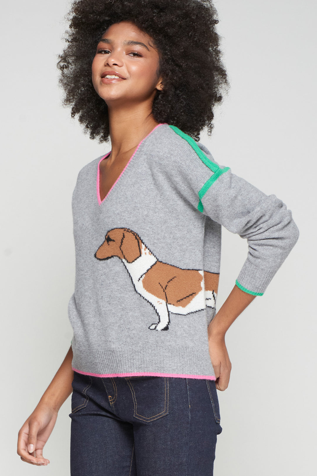 Woman wearing a gray sweater with a dog illustration on a plain background