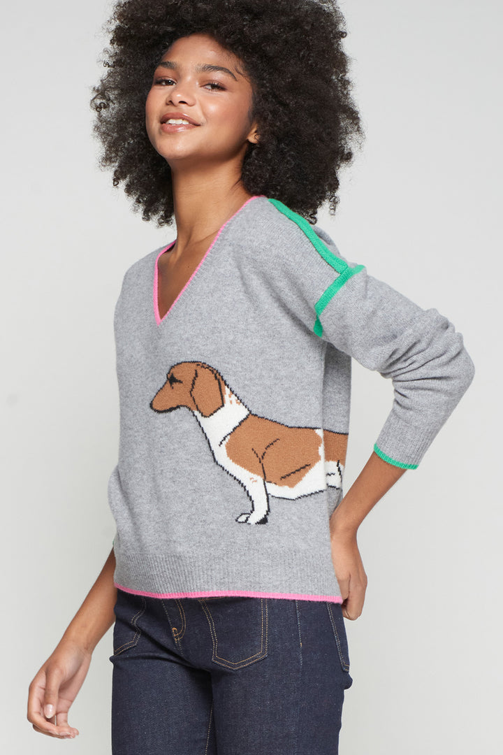 Woman wearing a gray sweater with a dog illustration on a plain background