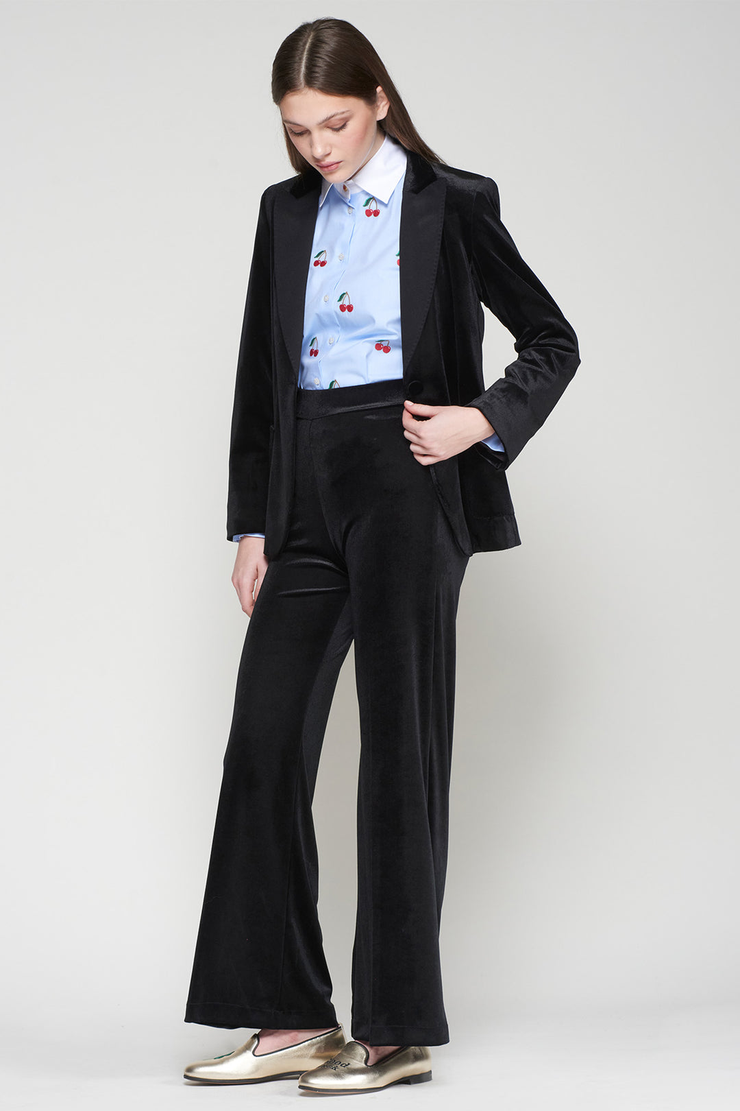 Woman wearing a black suit with a patterned shirt on a white background