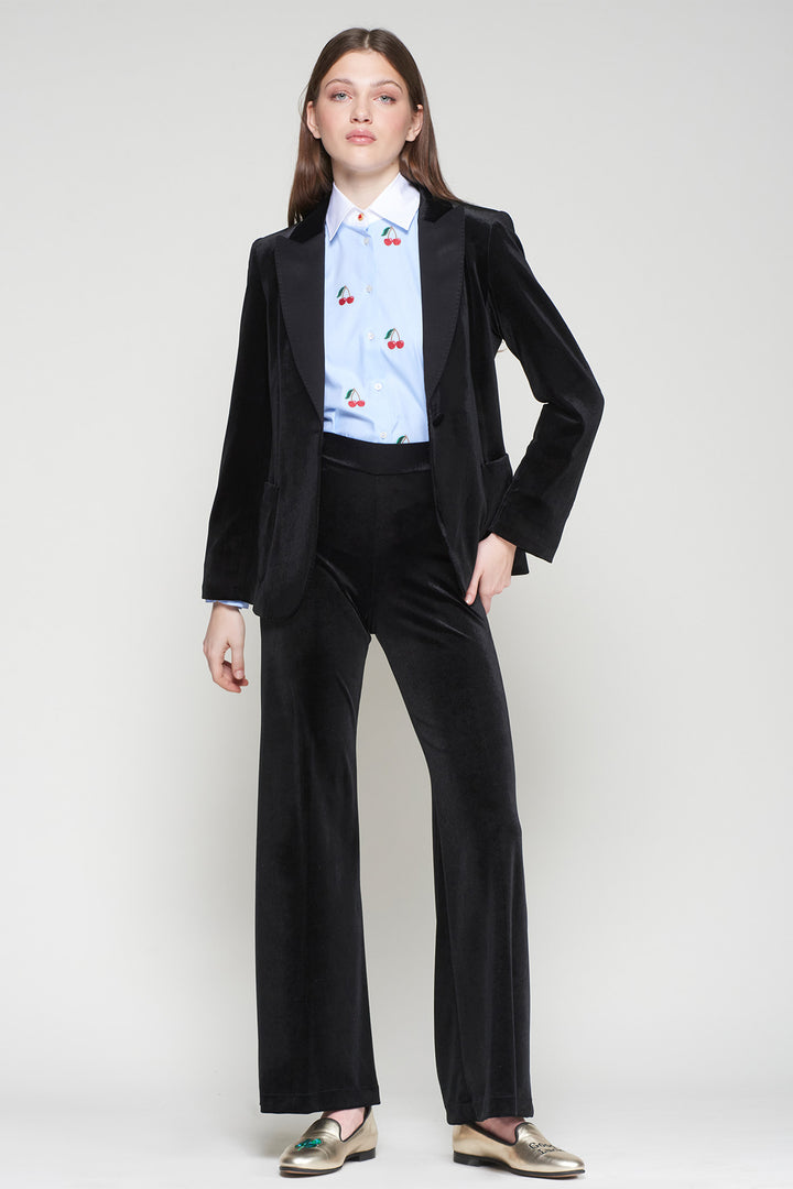 Person wearing a black suit with a light blue shirt featuring red cherries on a white background