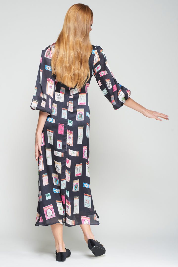Woman wearing a long, patterned dress on a plain background